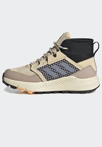 Zapatillas deportivas de media altura en beige y gris, que cuentan con materiales de malla y sintéticos, una suela texturizada y tres franjas reflectantes en el lateral.