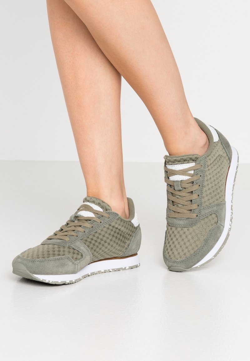 Grüne Mesh- und Wildledersneaker mit Schnürdesign, weißen Akzenten, strukturiertem Stoff und Gummisohle. Geeignet für den Freizeitgebrauch.