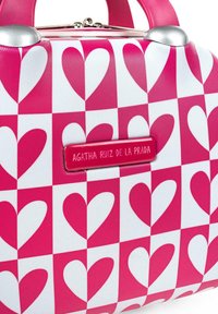Bolso a cuadros rosa y blanco con patrones de corazones, acentos metálicos y una placa rectangular con el logo "AGATHA RUIZ DE LA PRADA."