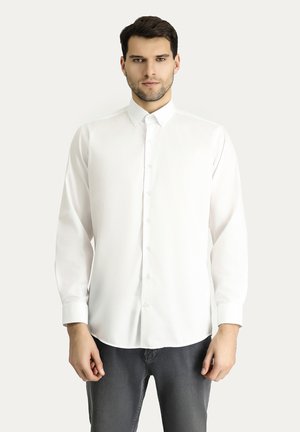 White long-sleeve button-up shirt with a classic collar, smooth texture, and a straight cut design. Paired with dark gray jeans.