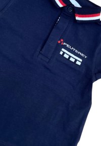 Polo blu navy con colletto a righe rosse e bianche, caratterizzato dal logo "Peuterey" e dettagli a motivo sul petto. Materiale in cotone.
