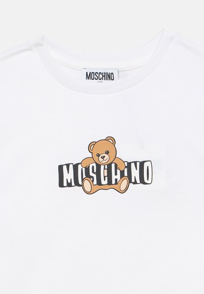 Λευκό βαμβακερό μπλουζάκι με γραφικό καφέ αρκούδας και λογότυπο «Moschino» σε έντονα μαύρα γράμματα. Στρογγυλή λαιμόκοψη με ριμπ τελείωμα.