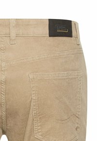 Beige Cordhosen mit strukturiertem Obermaterial, ausgestattet mit einem schwarzen Label mit dem "camel active"-Logo am Bund und einem Detail an der Gesäßtasche.