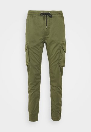 Olijfgroene cargo broek met een elastische tailleband en trekkoord. Beschikt over meerdere zijzakken en taps toelopende boorden. Glad oppervlak.
