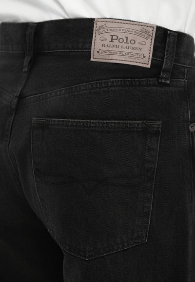 Jeans de denim preto com um design ajustado, apresentando um bolso traseiro e uma etiqueta de couro castanho claro rotulada "Polo Ralph Lauren" na cintura.