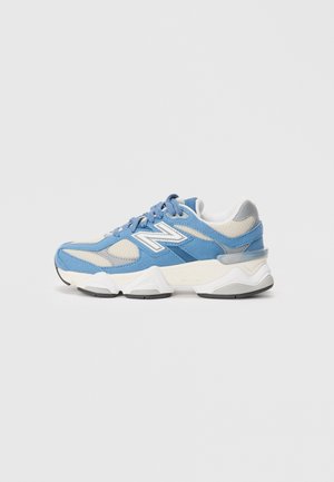 Blue and grey athletic shoe with mesh and suede materials, featuring a thick white sole, prominent logo, and textured accents.
