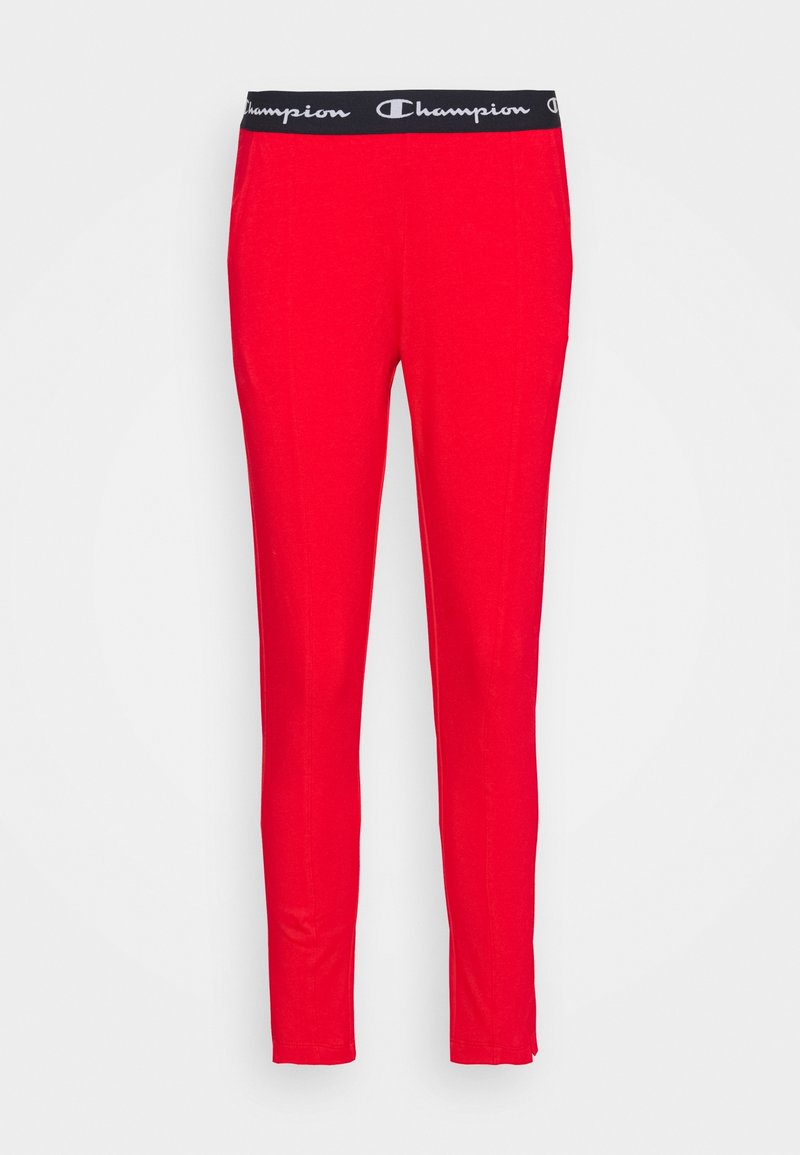 Röda idrottsbyxor med svart elastisk midja som har Champion-logotypen. Slät textur och slim fit som sträcker sig ner till anklarna.