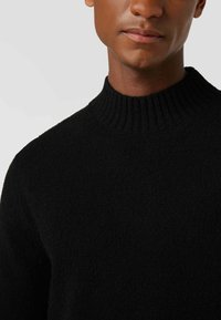 Schwarzer, gerippter Rollkragenpullover aus weichem Strickstoff, mit schmaler Passform und minimalistischem Design.