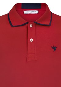 Camisa polo roja con cuello y detalles en azul marino. Presenta tres botones blancos y un pequeño logo de un pájaro azul en el pecho. Hecha de una tela texturizada.