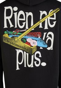 Schwarzer Hoodie mit einer farbenfrohen Illustration einer Werkzeugkiste, die mit verschiedenen Gegenständen gefüllt ist, und dem Spruch "Rien ne va plus" deutlich sichtbar.