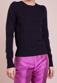 Navy blue knitted sweater featuring a diamond pattern, ribbed neckline and cuffs, with a fitted shape and long sleeves.