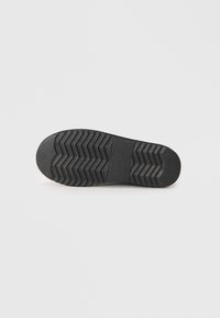 Black rubber shoe sole featuring a textured zigzag pattern for grip, a rounded toe, and smooth edges for durability.