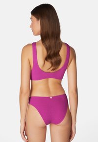 Rosa texturerad bikini med rundad rygg och breda remmar på toppen, ihopparad med lågriskade bottnar. Knappr accent bak.