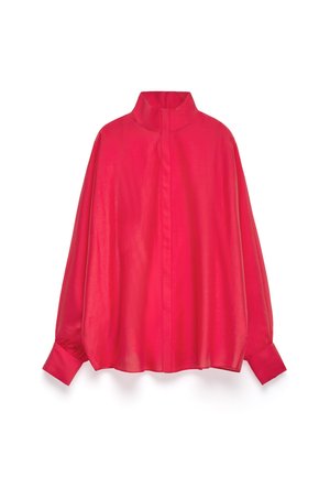 Blouse rouge surdimensionnée avec un col haut, fabriquée à partir d'un tissu lisse et brillant. Présente des manches longues et des poignets à volants.