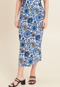 Gonna maxi con un motivo floreale blu e nero su sfondo bianco, con una silhouette aderente e uno spacco laterale. Indossata con sandali neri con tacco a blocco.
