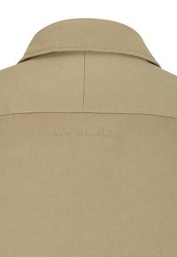 Beige shirt collar with a textured finish, featuring an embroidered logo "esmé studios" on the back. Tailored design with a clean silhouette.