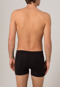 Czarne bokserki wykonane z gładkiego materiału, zapewniające dopasowanie i elastyczny pasek w talii. Model pokazany jest z tyłu.