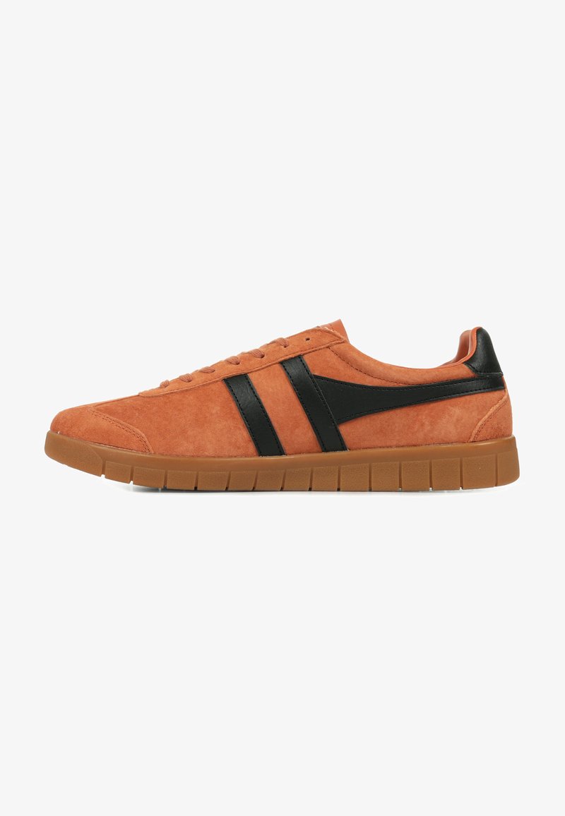Sneaker in suede arancione con dettagli in pelle nera, caratterizzato da una punta arrotondata, suola piatta e design con lacci. Superficie testurizzata e dettagli minimi.