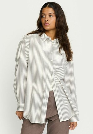 Camicia a righe bianca e marrone chiaro. Presenta un colletto, maniche lunghe e una tasca sul petto. Vestibilità ampia con orlo curvo.