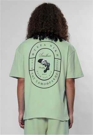 Lys grøn bomulds t-shirt med et sort grafisk print af en statue og tekst på ryggen. Kortærmet og afslappet pasform.