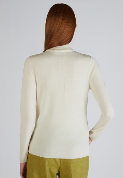 Crème lange mouwen top met een aansluitende kraag en centrale achternaad detail, gemaakt van een gladde knit stof. Gecombineerd met lichtgroene broek.