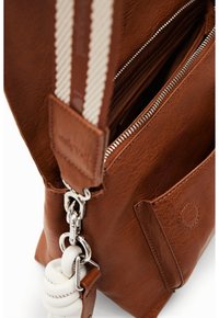 Ruskea nahkainen käsilaukku hopeisilla metalliosilla, jossa on vetoketjusuljin, raidallinen olkahihna ja teksturoitu pinta. Mukana ulkotasku.