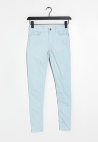 Jeans skinny de denim azul claro con cierre de botón, cinco bolsillos y detalles de costura mínimos. Diseñados para una silueta ajustada.