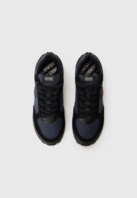 Navy blue athletic shoes featuring a textured upper, black accents, lace-up design, and a rubber sole with a circular logo detail.