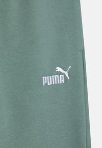Zeleni pamuk s mješavinom vlakana s mekom teksturom; sadrži izvezeni bijeli logo "PUMA" s dizajnom skakačke mačke.