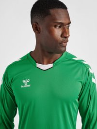 Grøn atletisk trøje med V-hals-design, der har hvide accenter på skuldrene. Fremstillet af et glat, let stof. Brandlogoet vises.