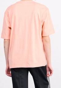 T-Shirt mit kurzen Ärmeln und lockerer Passform aus weichem Pfirsichbaumwollstoff. Einfaches Design mit rundem Halsausschnitt und geradem Saum.