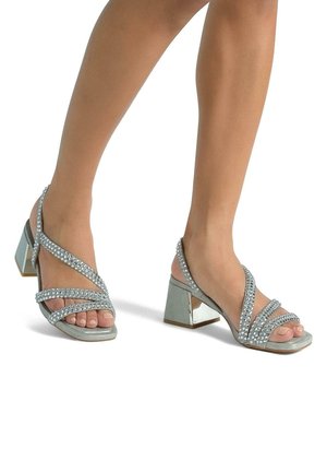 Sandali con tacco alto argentati e punta aperta, caratterizzati da cinturini incrociati in strass e un tacco a blocco con un accento a specchio.
