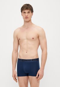 Boxer briefs bleu marine en tissu lisse, avec un logo Diesel noir sur la ceinture et une coupe ajustée.