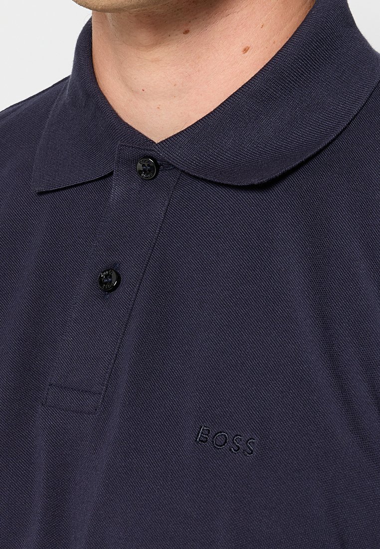 Polo navy in tessuto testurizzato, con colletto e patta a due bottoni. Piccolo logo "BOSS" ricamato sul petto.