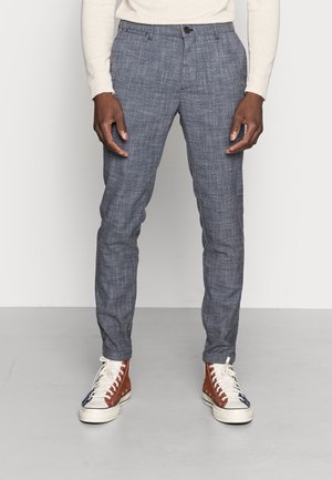Lätta blå mönstrade byxor, slim fit med knappstängning. Kombinerade med högskor i brunt, med vita och blå accenter.