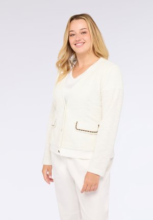 Cardigan bianco with texture e scollo a V, con due tasche frontali bordate di nero. Un sistema di chiusura con bottoni e una vestibilità rilassata completano il design.