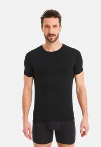 Black short-sleeve t-shirt with a round neckline, fitted design, smooth texture, and minimal stitching detail, worn over black underwear.