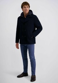 Marineblauer Peacoat mit strukturiertem Finish und doppelt geknöpftem Design, kombiniert mit hellblauen Hosen und dunklen Schuhen. Verfügt über eine Kapuze.