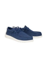 Scarpe in camoscio blu navy con suola in gomma bianca, caratterizzate da un accento testurizzato sul tallone e lacci blu. Progettate per un uso casual.