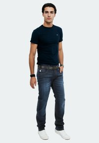 Navy t-shirt paired with dark blue jeans and white sneakers, featuring a fitted design and subtle texture in the fabric.