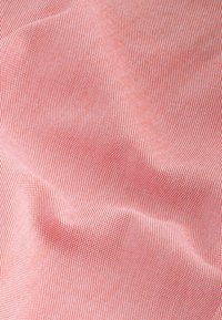 Gros plan sur un tissu à petits carreaux rouges et blancs avec des plis doux et une surface légèrement texturée.