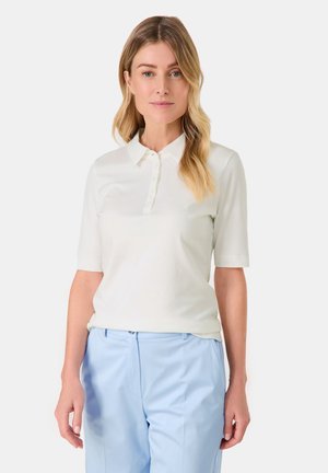 White short-sleeve polo shirt with button front and soft texture, complemented by light blue trousers. Simple design with a classic collar.