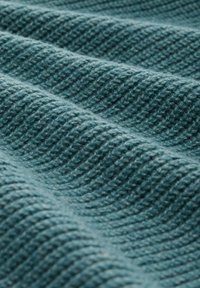 Tissu texturé avec un motif ondulé de couleur sarcelle. Le matériau semble doux avec une structure tissée dense.