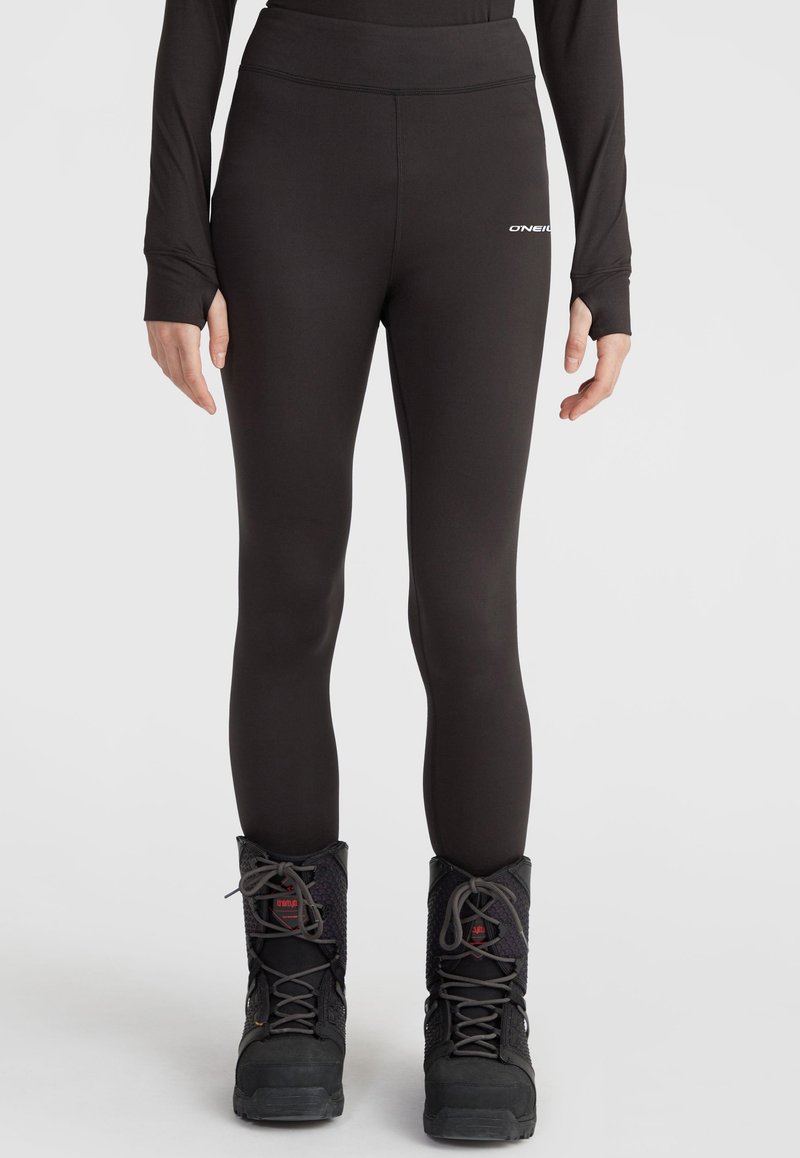 Black athletic leggings with a high waistband and smooth texture, featuring a small logo detail on the left hip. Worn with black boots.
