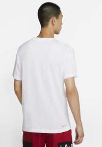 Hvid kortærmet T-shirt med rund hals og en afslappet pasform. Stoffet ser glat og let ud, med en lille logodetalje nær kanten.