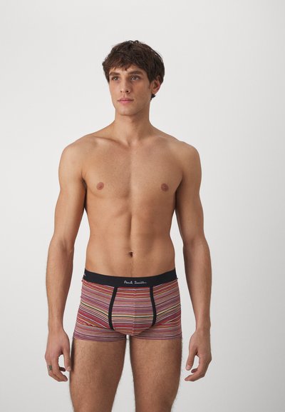 Caleçon rayé dans des couleurs vives, avec une taille noire portant un logo blanc, fabriqué à partir d'un matériau doux et extensible pour le confort.