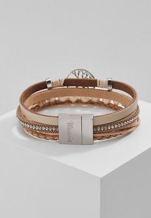 Flerlags beige læderarmbånd med sølvspænde, rhinsten, flettede detaljer og perle-lignende perler på hvid piedestal.