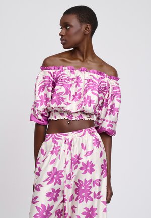 Off-shoulder cropped top met roze bloemenpatronen op een crèmekleurige achtergrond. Bijpassende loszittende broek met een elastische tailleband.