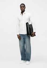 Weiß gestreiftes Langarmshirt, blaue Denim-Weitbein-Jeans, schwarze Tragetasche und weiße Turnschuhe. Einfaches Design mit entspannter Passform.