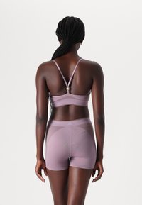 Lys lilla trenings-BH og matchende shorts i en tettsittende, sømløs design. Teksturert stoff med subtile mønstre og justerbare stropper.
